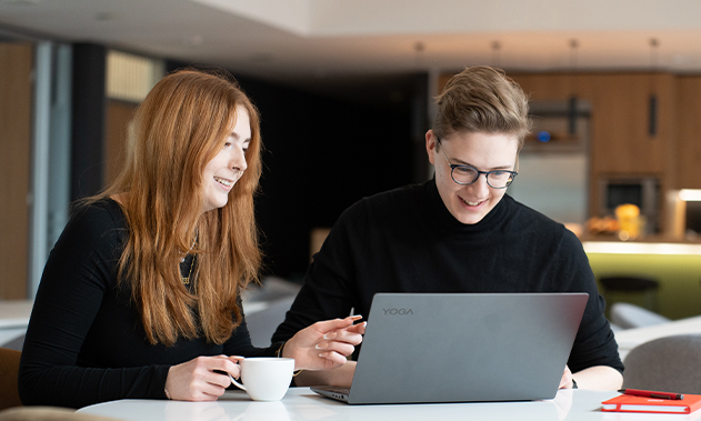 Zwei Personen schauen gemeinsam auf einen Laptop.